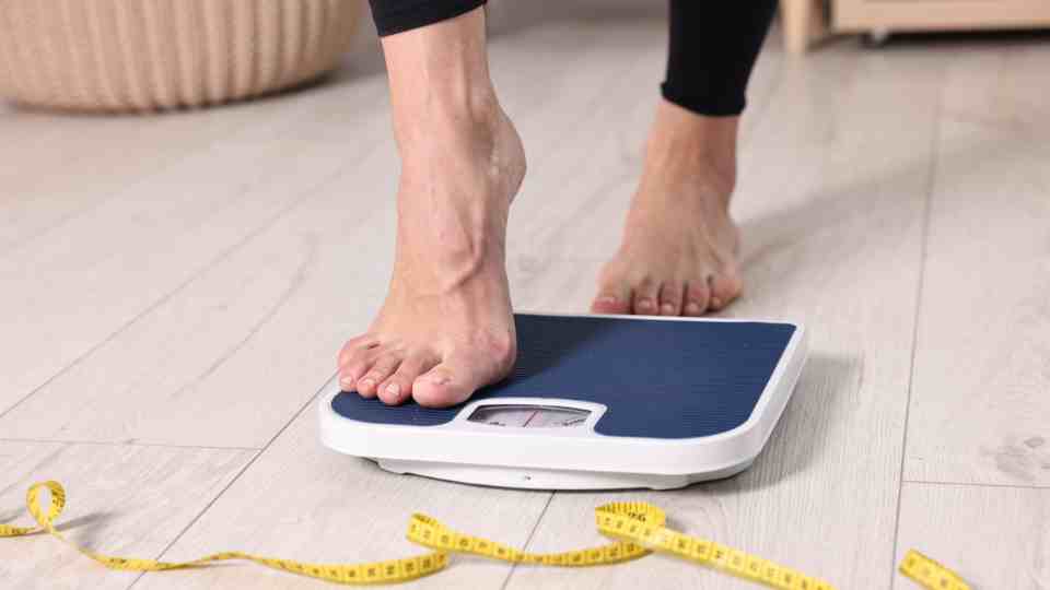 Woman stepping on scale to measure weight loss