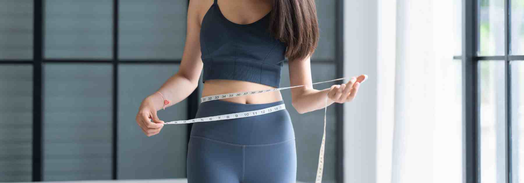 Woman mesuring weight loss with tape measure